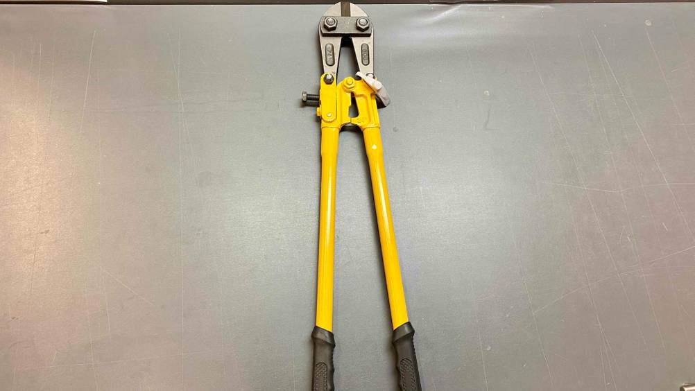 Im Test: Auf einer grauen Fläche liegt ein Bolzenschneider vertikal.