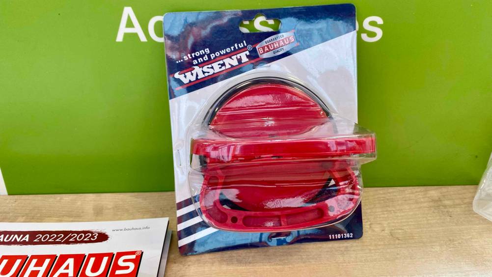 Im Test: Ein Saugheber von oben in der Originalverpackung an einer grünen Wand lehnend.