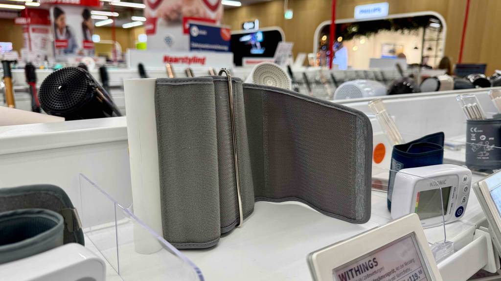 Ein Bluetooth-Blutdruckmessgerät im Test steht auf einem Verkaufsregal inmitten anderer Produkte.