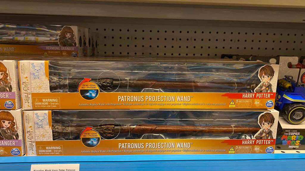 Harry Potter Zauberstab getestet: mehrere verpackte Zauberstäbe liegen gestapelt in einem Regal.