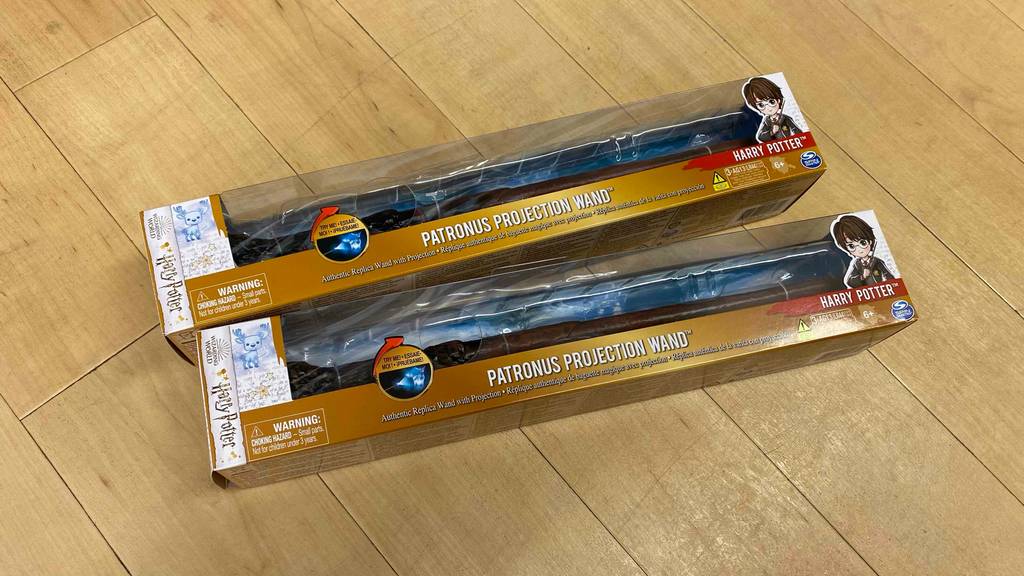 Harry Potter Zauberstab im Test: Zwei verpackte Zauberstäbe liegen übereinander auf einem Holzboden.