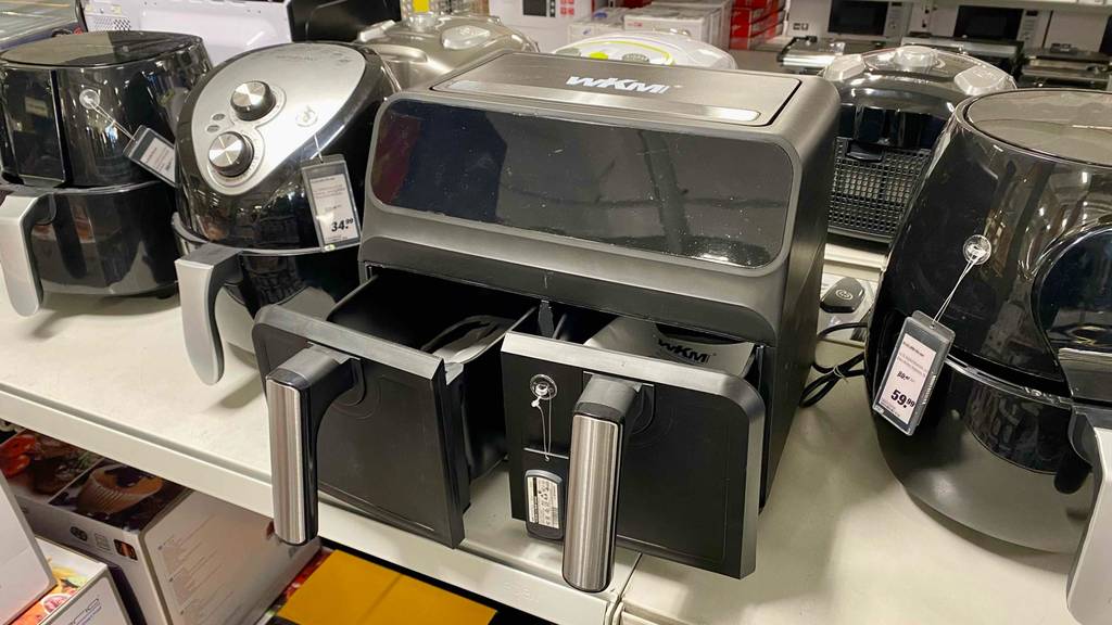 Doppelfritteusen-Test: Ansicht von oben auf ein schwarzes WKM-Modell mit zwei geöffneten Schubladen auf einem Einkaufsregal mit weiteren Fritteusen.
