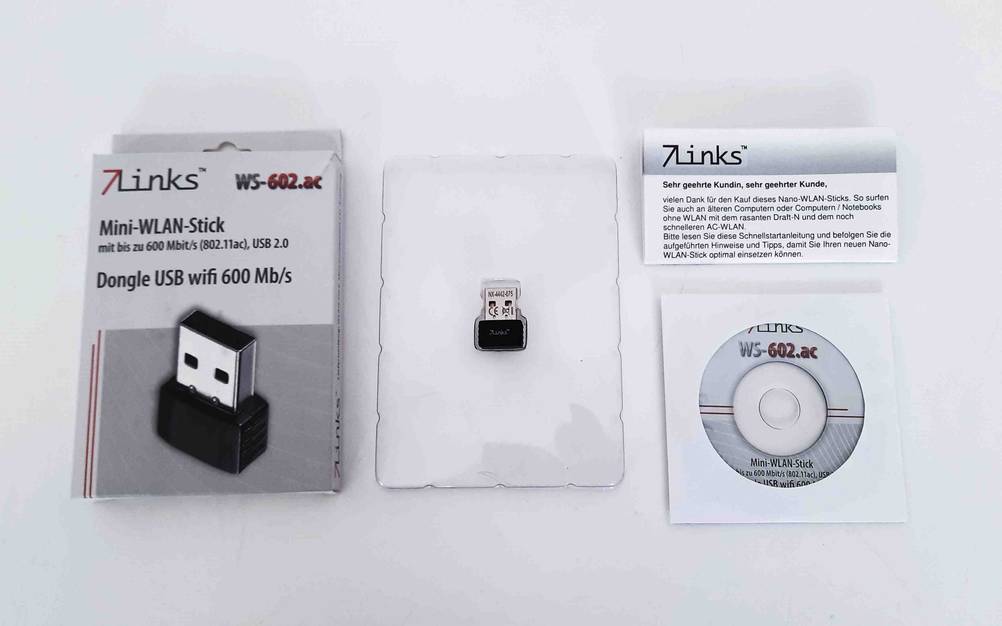 WLAN-Stick-Test: Die Originalverpackung, der Stick, die Betriebsanleitung und eine CD nebeneinander auf einer hellen Fläche angeordnet.