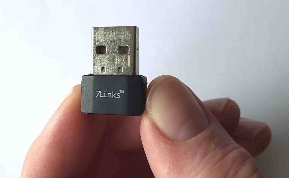 Eine Hand hält einen getesteten WLAN-Stick zwischen den Fingern.