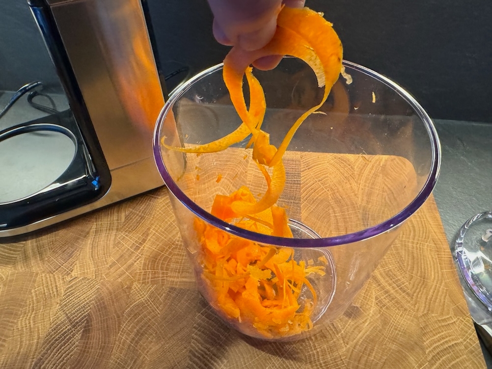 Eine Hand hebt Karottenspiralen aus einem durchsichtigen Behälter.