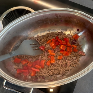 Mit einem Pfannenwender werden Paprikastücke im Wmf 0788009990 mit Hackfleisch gemischt