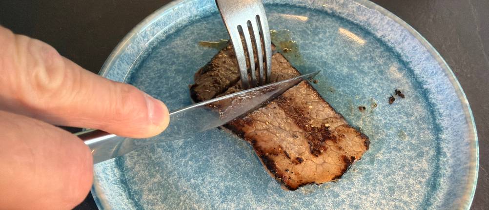 Ein Stück Steak wird mit dem Wmf 1291716046 geschnitten