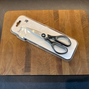 Die WMF 18.7920.6100 liegt eingepackt auf einem Holzbrett