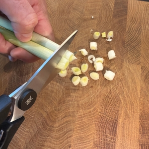 Mit der WMF 18.7920.6100 wird eine Frühlingszwiebel geschnitten