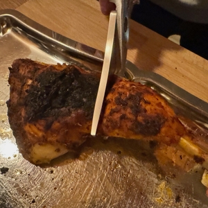 Mit der WMF-1887719990-Geflügelschere wird Fleisch geschnitten, was auf einem silbernen Tablett liegt