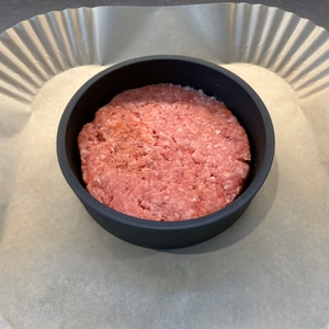 Ein Burger-Patty liegt in der Wmf-BBQ-Burgerpresse 690296030