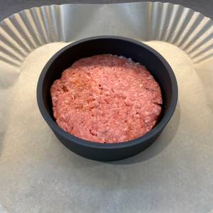 Ein Burger-Patty liegt in der Wmf-BBQ-Burgerpresse 690296030