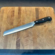 Das WMF-Brotmesser mit Doppelwellenschliff auf einem Brett liegend.