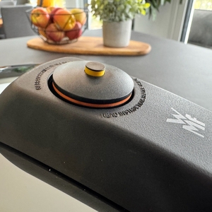 Ein Knopf auf dem Deckel des WMF-Dampfkochtopfs in Nahaufnahme, der gelbe Pin und der erste Ring sind zu sehen.