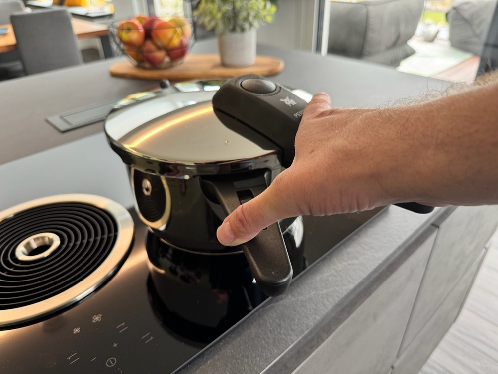 Eine Hand verriegelt den Deckel des WMF-Dampfkochtopfs.