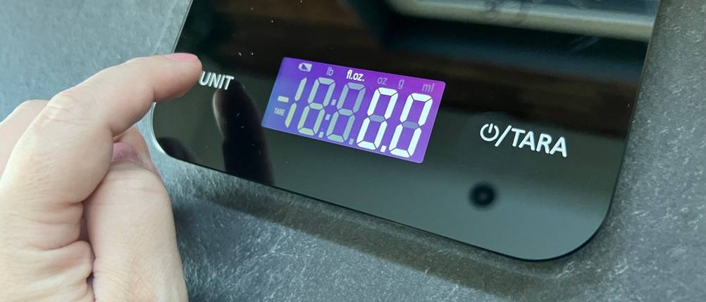 Ein Finger drückt die Unit-Funktion auf der WMF digitalen Küchenwaage schwarz. 