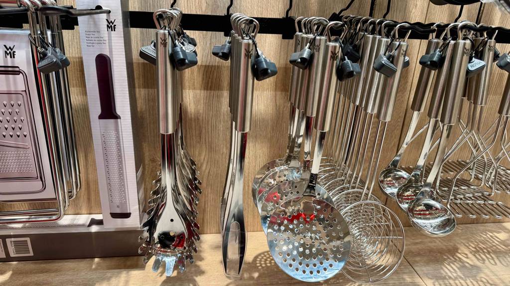 Eine getestete Fleischgabel aus Edelstahl hängt neben weiteren Kochutensilien an einem Verkaufsregal.
