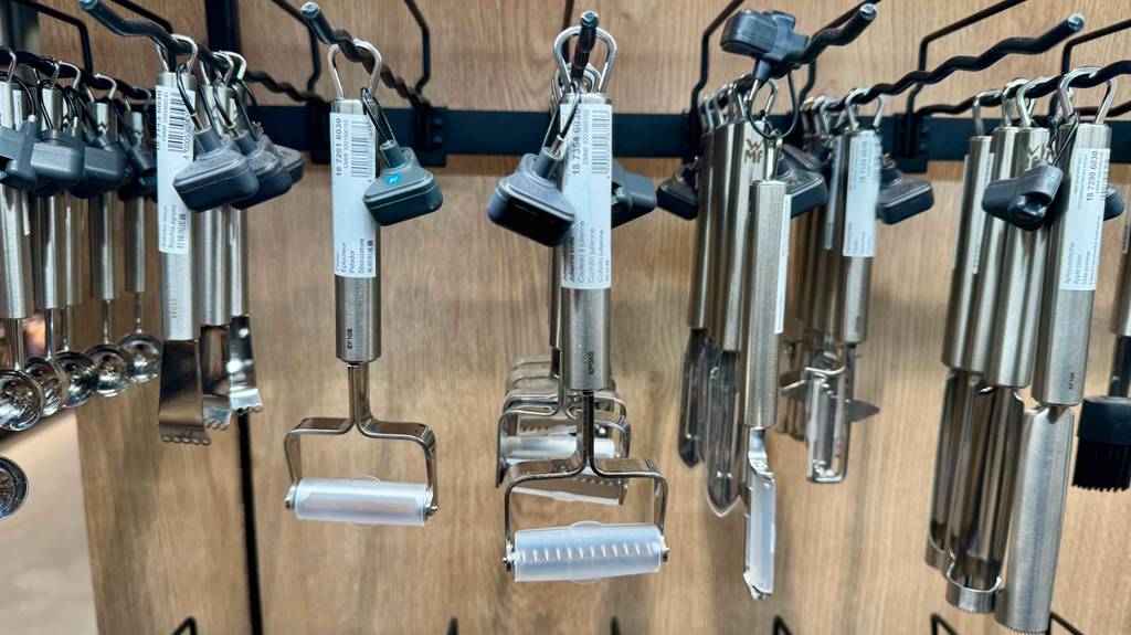 Mehrere Edelstahl-Julienne-Schneider im Test hängen hintereinander an einem Verkaufsstand neben weiteren Küchenutensilien.