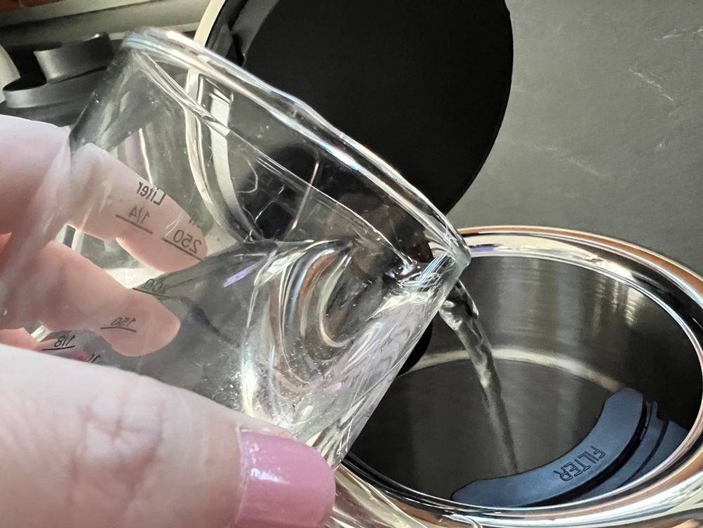 Wasser mit Messbecher eingießen