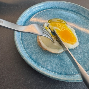 Fertiges Spiegelei wird mit Messer und Gabel angeschnitten