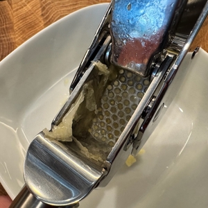 Eine Obenansicht der geöffneten Knoblauchpresse mit Schalenresten.