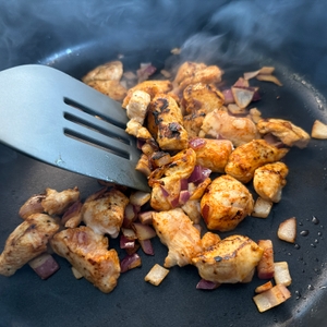 Fleisch wird in der Wmf-Schmorpfanne 28 cm mit einem Pfannenwender mit Zwiebeln gemischt