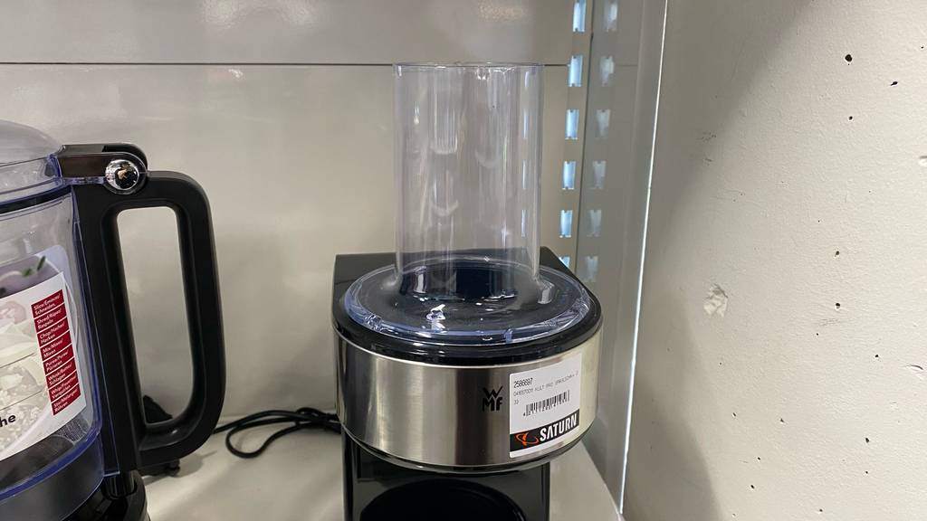 Elektrischer Spiralschneider im Test: ein schwarzes WMF-Modell mit transparentem Aufsatz steht im Verkaufsregal vor weißer Wand.