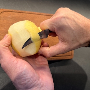 Eine Hand schält mit dem WMF-Schälmesser eine Nashi-Birne.