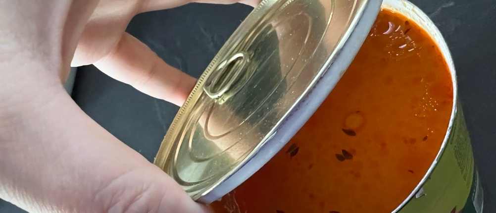 Eine Hand öffnet einen Deckel, der mit Dosenöffner WMF-Tin-Up geöffnet wurde.