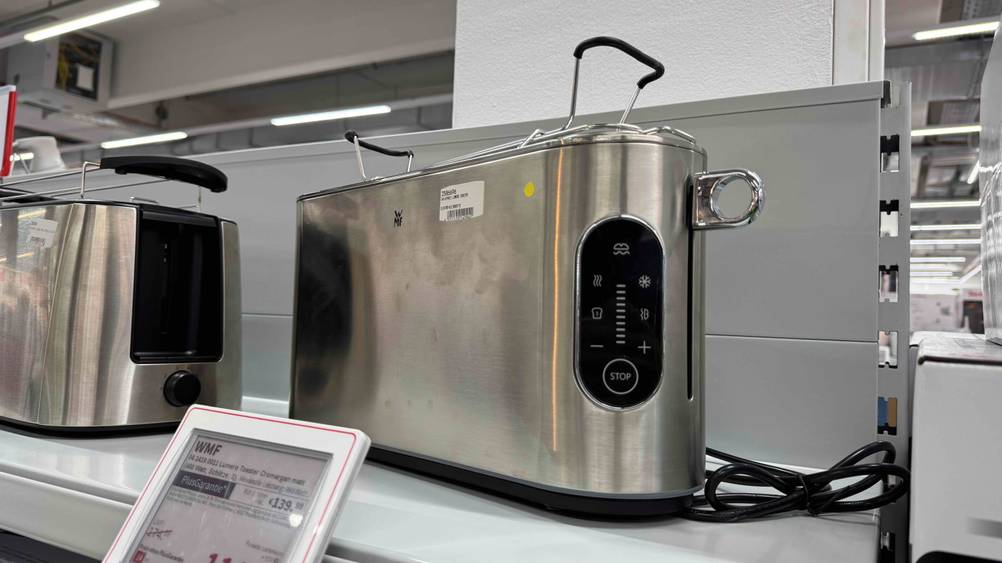 Ein getesteter WMF-Toaster von der Seite auf einem. Regal mit Preisangaben.