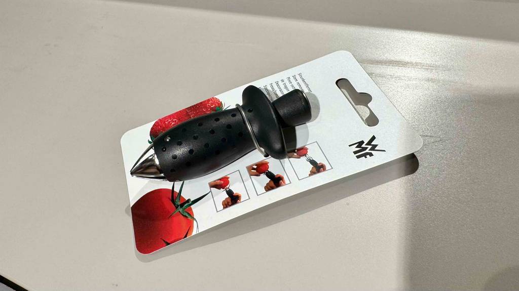 Im Test: Ein Tomatenstrunkentferner von WMF liegt mit der Verpackung auf einem hellen Untergrund.