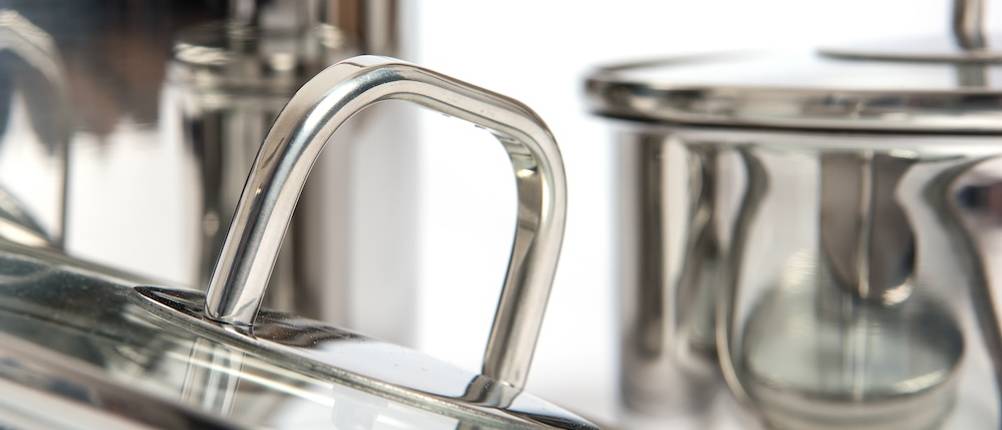 Griffe des WMF-Topfsets im Test: Im Vordergrund steht ein angekippter Glasdeckel mit Edelstahlgriff. Im Hintergrund ist noch ein Edelstahl-Kochtopf erkennbar.