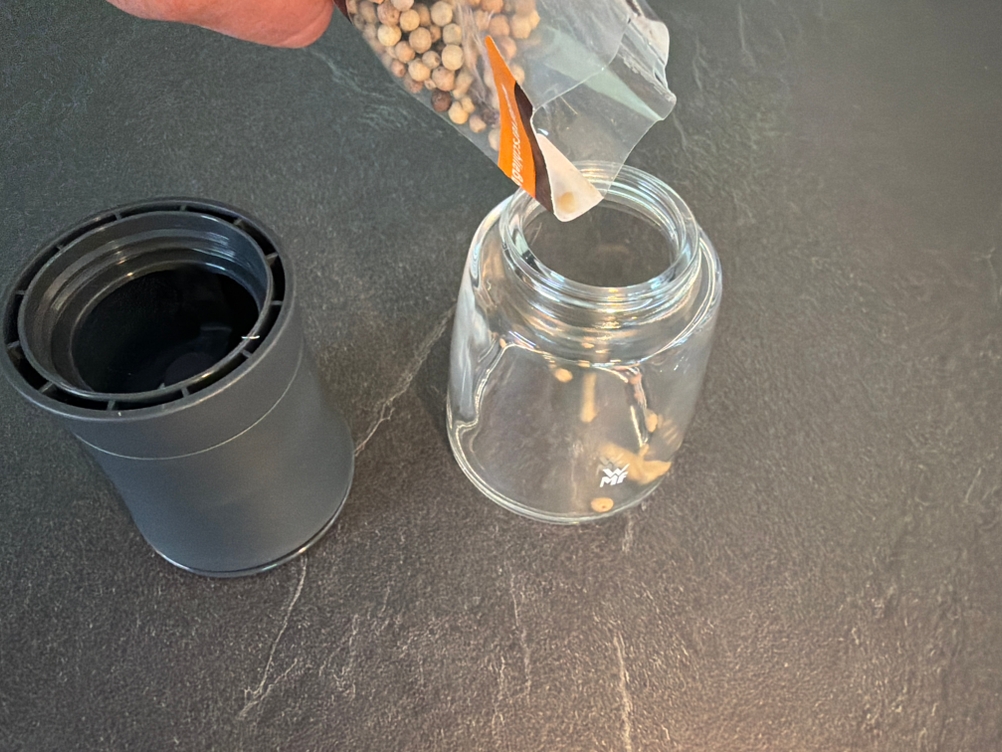 Pfefferkörner werden in einen Glasbehälter der Wmf-Trend-Gewürzmühlen gegeben.