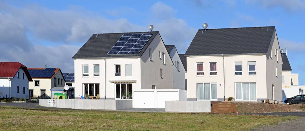 Zwei Mehrfamilienhäuser stehen nebeneinander in einem Neubaugebiet.