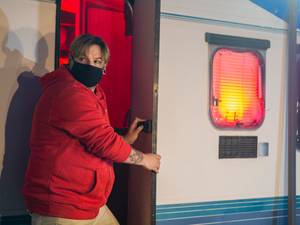 Wohnwagenversicherungen im Test: Ein Mann im roten Pullover bricht in einen Wohnwagen ein.