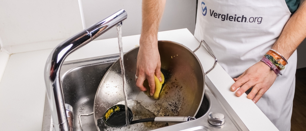 Eine Person reinigt einen Wok per Hand im Waschbecken
