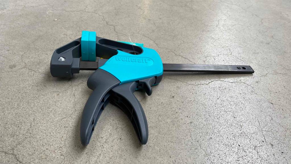 Im Test: Wolfcraft Einhandzwinge liegt quer auf Betonboden.
