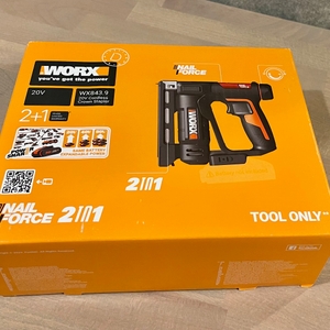 Die Verpackung des WORX WX843.9 Akku-Tackers liegt auf einem Holzboden. Auf dem Karton sind das Produktbild, Modellname und kompatible Akkusysteme zu sehen.