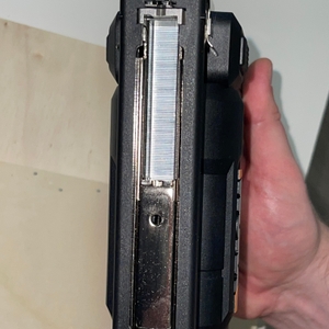 Der WORX WX843.9 Akku-Tacker wird von vorne gezeigt, mit Blick auf das eingeführte Magazin voller Klammern. Eine Hand hält das Gerät im Einsatzgriff.