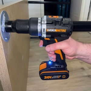 Der Worx Nitro WX352 Akkubohrer wird beim Schrauben in ein Holzbauteil verwendet. Die Hand des Nutzers umfasst das Werkzeug, während eine LED-Leuchte aktiviert ist.