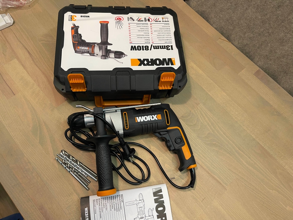 Die Worx-WX318-Schlagbohrmaschine mit Transportkoffer, Netzkabel, mehreren Betonbohrern und Bedienungsanleitung. 