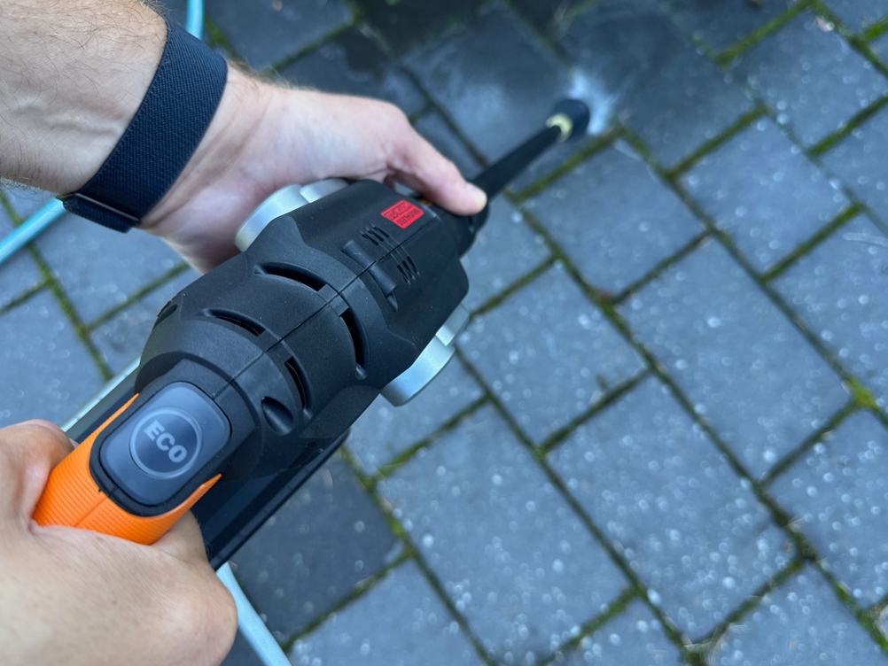 Zwei Hände greifen den Worx-WG633E-Hydroshot-Akku-Hochdruckreiniger. 