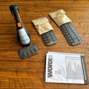 Der Lieferumfang der Worx WG801E.9 liegt auf einem Tisch.