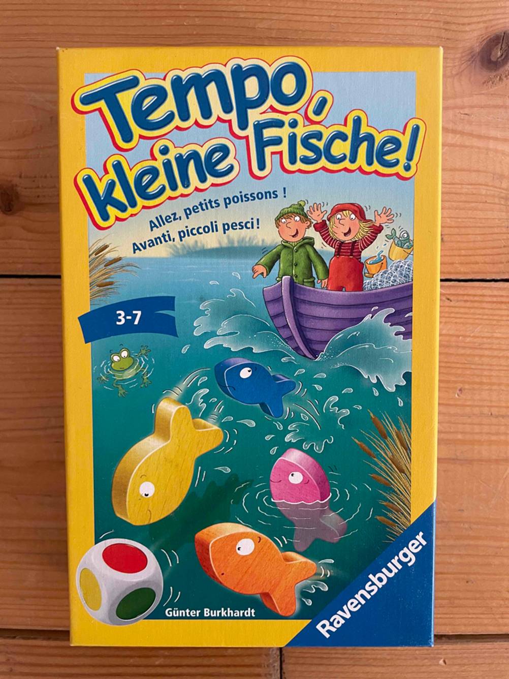 Vorderseite der Originalverpackung der getesteten Würfelspiele auf einer Holzfläche.