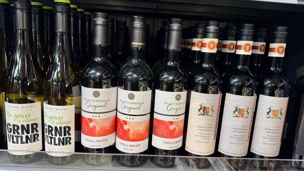 Trollinger-Test: Mehrere Flaschen Wein stehen nebeneinander auf einem Weinregal im Supermarkt.