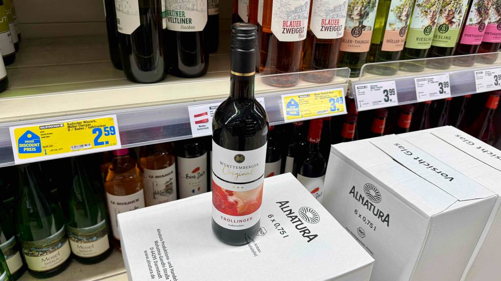 Trollinger-Test: Eine Flasche Wein steht auf einem Karton vor einem Weinregal im Supermarkt.
