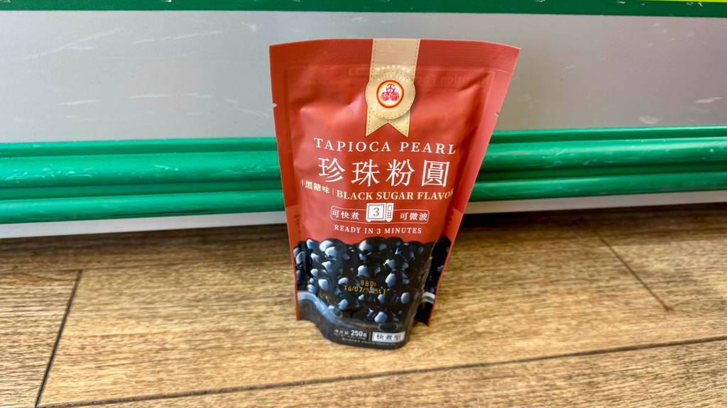 Die Verpackung von getesteten Bubbletea-Perlen steht auf einem Boden vor einer grünen Leiste.