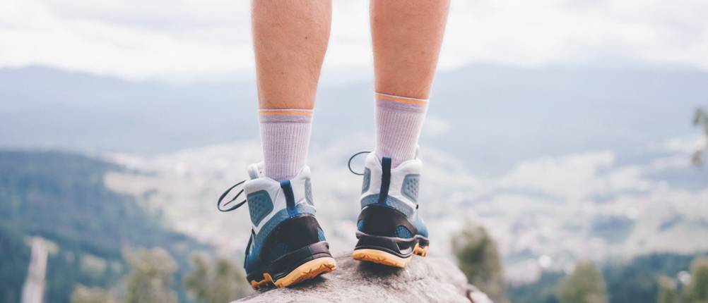 Wundersocks-Test: Mann steht beim Wandern auf einem Felsen und blickt in Richtung Tal.