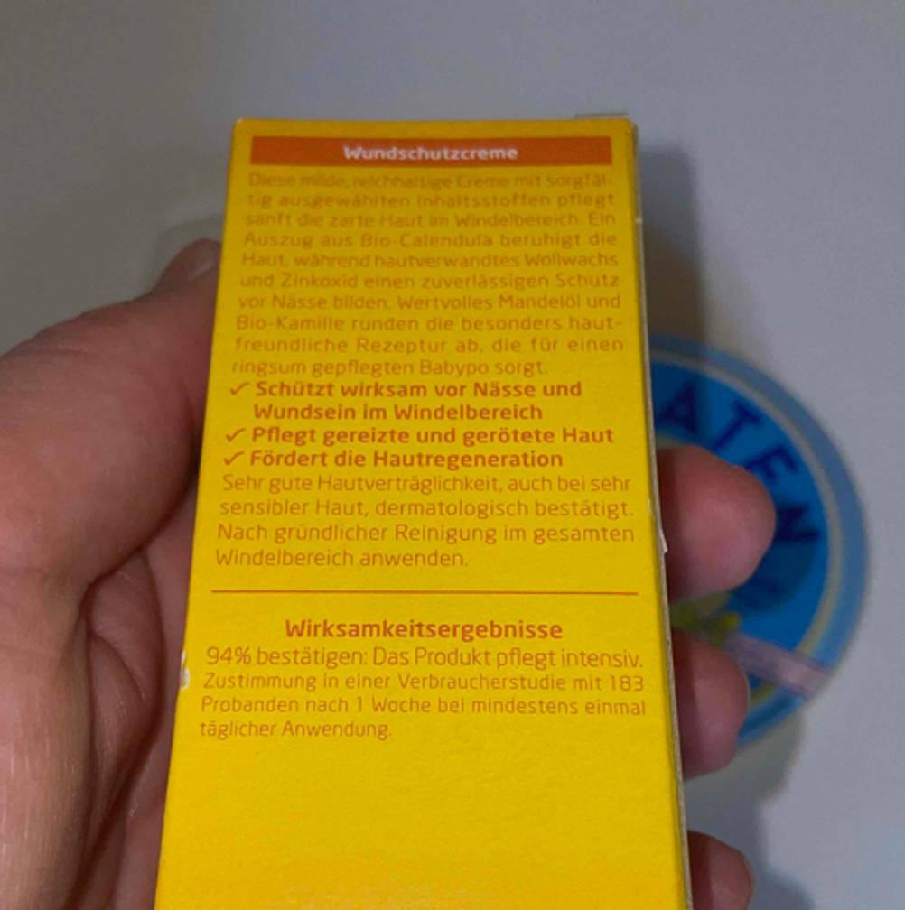 Rückseite einer Packung der getesteten Wundschutzcreme von einer Hand gehalten.