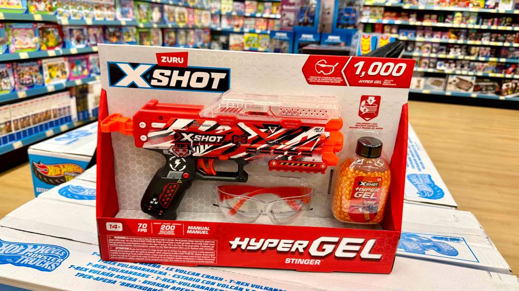 Gel-Ball-Blaster im Test: Das Set, bestehend aus einer Pistole, der Sicherheitsbrille und den Gel-Kugeln, steht innerhalb der Verpackung inmitten eines Spielzeugladens.